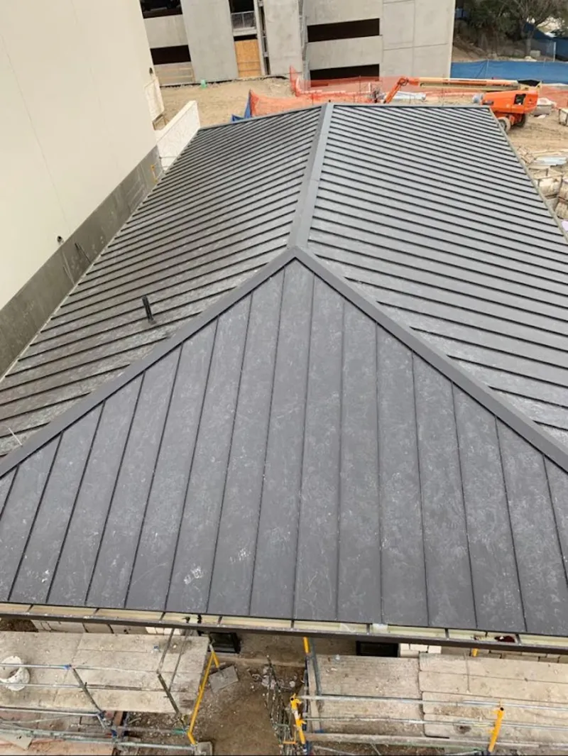 Commercial metal roof construction with crane equipment in Vista